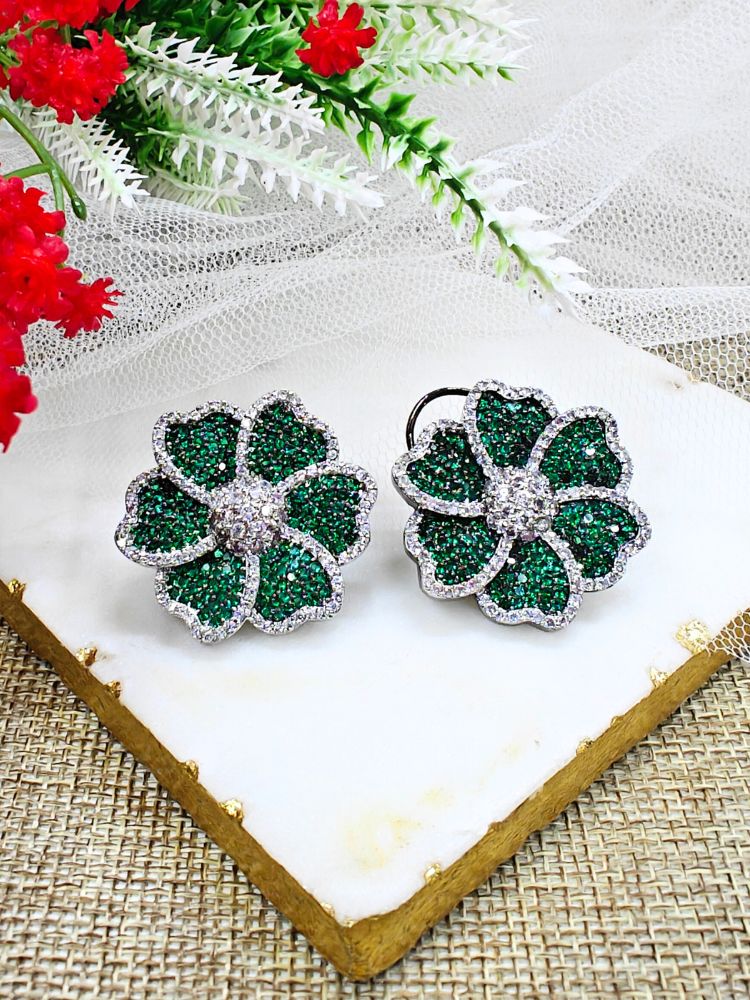 Dark Green Daisy Earrings, adorned with green colored stones and sparkling American Diamonds in close setting. They come with a classic flap at the back. The close setting earrings are showcased on a white marble slab with red and white artificial flowers—ideal for complementing your favorite cocktail gown. 