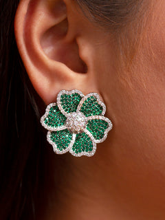 Close-up of a woman wearing an ornate  Western Green Diamond Studs Earrings with American Diamond and Colored Stones. Party wear outfit completed with a lightweight American diamond Studs Earrings. Close-up of sparkling American diamond Stud earrings for party wear.