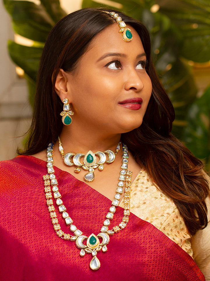 Close-up of a woman wearing an ornate traditional (Gold Polish) Dark Green Long Kundan jewellery set and earrings and a Choker and Mangtikka with Kundan and Colored Stones. Wedding celebration look enhanced with a statement Kundan necklace. Bride wearing a royal Kundan artificial necklace for wedding rituals.