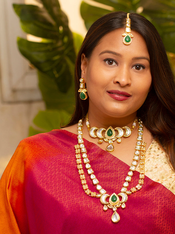 Close-up of a woman wearing an ornate traditional (Gold Polish) Dark Green Long Kundan jewellery set and earrings and a Choker and Mangtikka with Kundan and Colored Stones. Wedding celebration look enhanced with a statement Kundan necklace. Bride wearing a royal Kundan artificial necklace for wedding rituals.