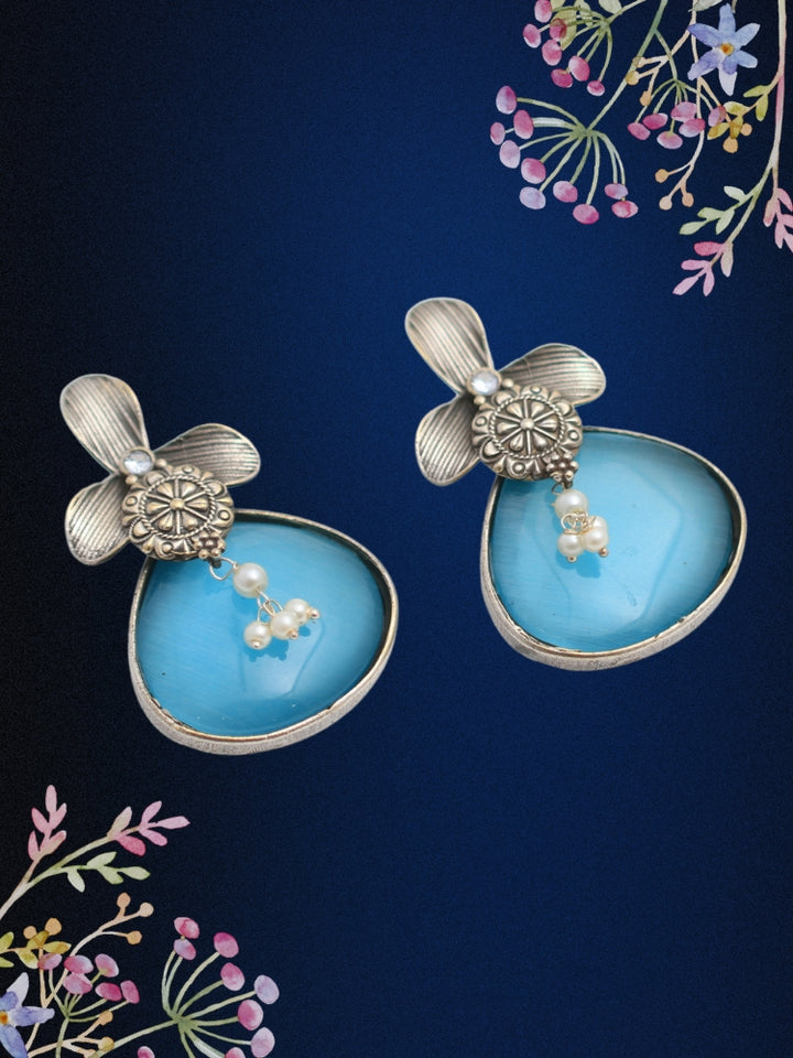 David Blue oxidized Earrings feature silver flower-shaped tops, decorative floral details, and blue teardrop stones. Small white pearls dangle at the center, adding a touch of elegance to these stylish german silver earrings.  Oxidized earrings from the oxidized jewelry collection. 
