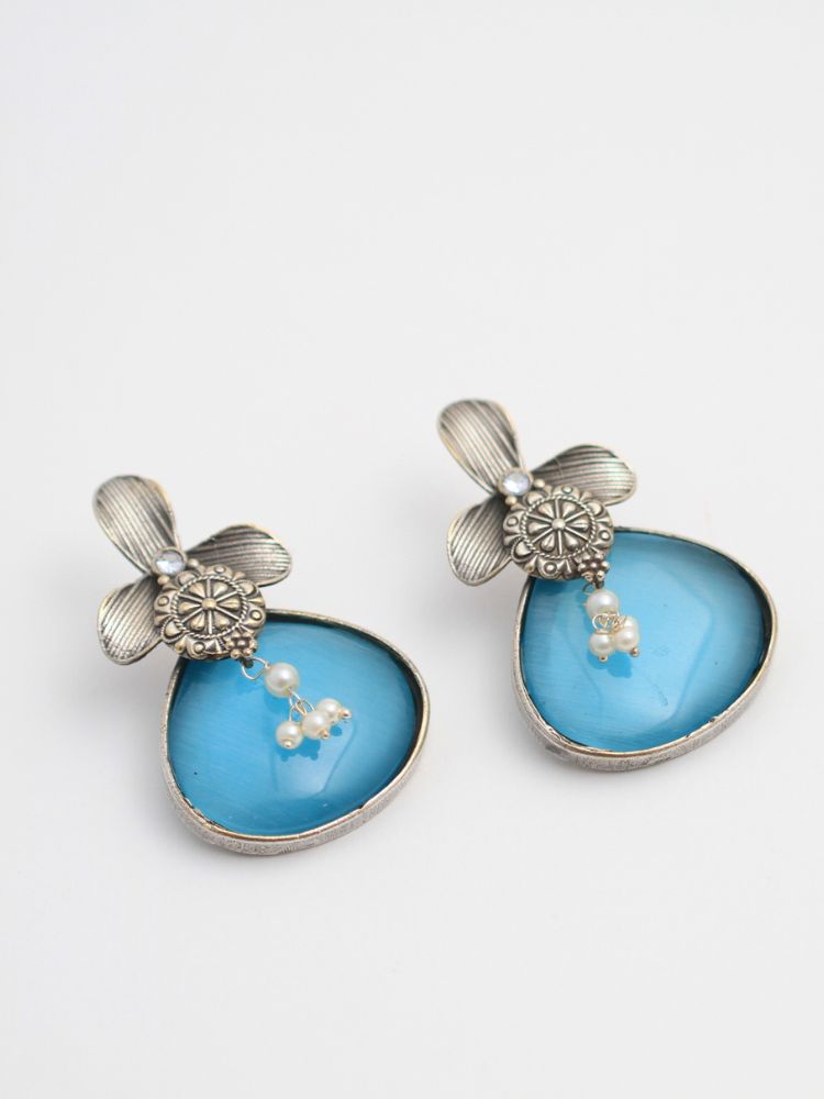 David Blue oxidized Earrings feature silver flower-shaped tops, decorative floral details, and blue teardrop stones. Small white pearls dangle at the center, adding a touch of elegance to these stylish german silver earrings.  Oxidized earrings from the oxidized jewelry collection. 