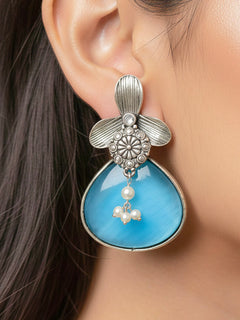 Close-up of a woman wearing an ornate Western (Silver Polish) Blue Oxidised Earrings with Blue Colored Stone and Pearl. Festive Diwali look styled with premium artificial  Oxidised earrings. 