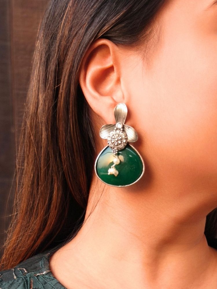 David dark-green oxidized Earrings feature silver flower-shaped tops, decorative floral details, and dark-green teardrop stones. Small white pearls dangle at the center, adding a touch of elegance to these stylish german silver earrings.  Oxidized earrings from the oxidized jewelry collection. 
