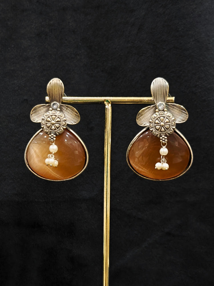 Close-up of an ornate Western (Silver Polish) English Brown Oxidised Earrings with English Brown Colored Stone and Pearl. Festive Diwali look styled with premium artificial  Oxidised earrings. 