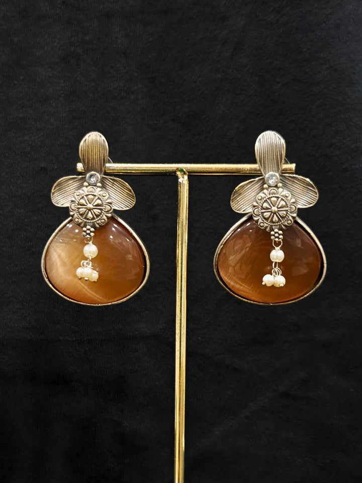 Close-up of an ornate Western (Silver Polish) English Brown Oxidised Earrings with English Brown Colored Stone and Pearl. Festive Diwali look styled with premium artificial  Oxidised earrings. 