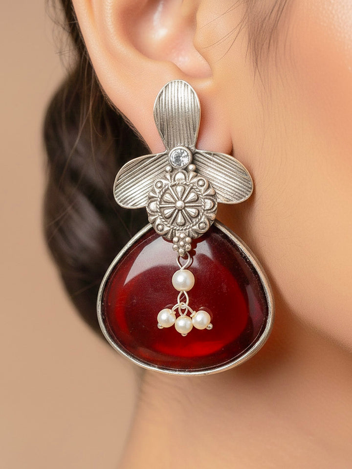 Close-up of a woman wearing an ornate Western (Silver Polish) Maroon Oxidised Earrings with Maroon Colored Stone and Pearl. Festive Diwali look styled with premium artificial  Oxidised earrings. 