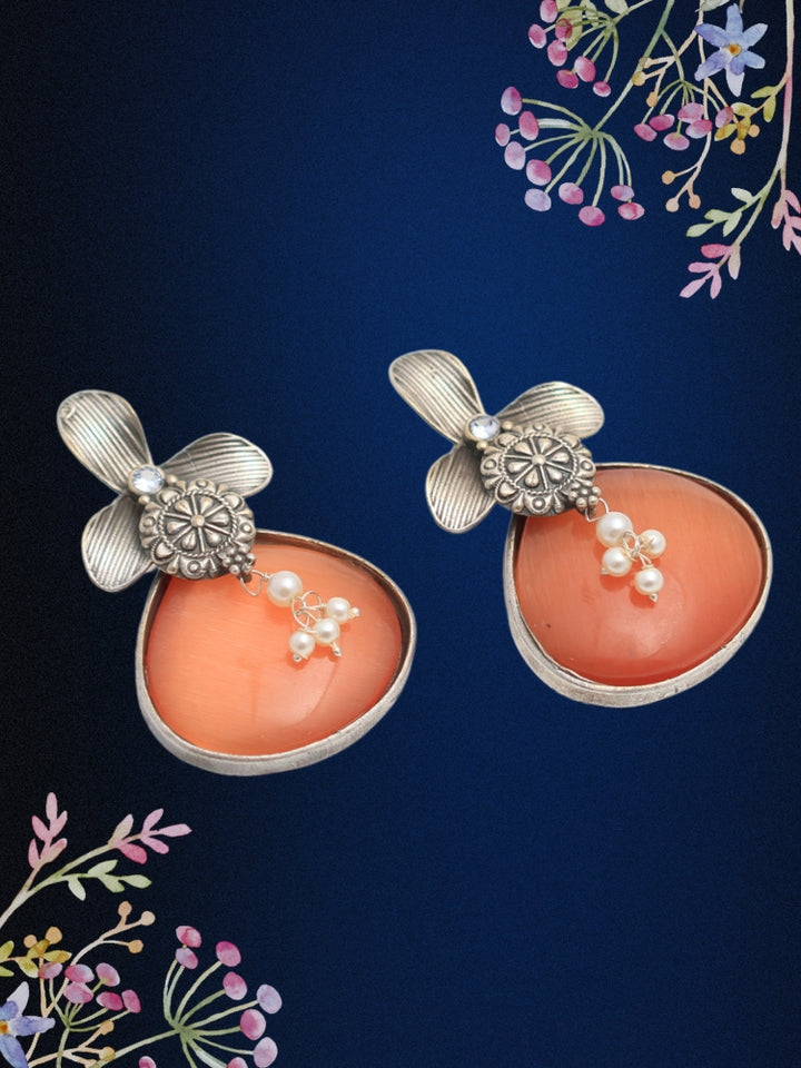 David Orange oxidized Earrings feature silver flower-shaped tops, decorative floral details, and Orange teardrop stones. Small white pearls dangle at the center, adding a touch of elegance to these stylish german silver earrings.  Oxidized earrings from the oxidized jewelry collection. 