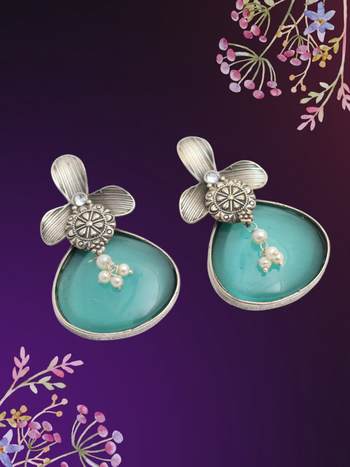 David Sea Green oxidized Earrings feature silver flower-shaped tops, decorative floral details, and Sea Green teardrop stones. Small white pearls dangle at the center, adding a touch of elegance to these stylish german silver earrings.  Oxidized earrings from the oxidized jewelry collection. 
