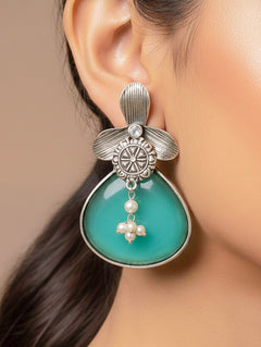 Close-up of a woman wearing an ornate Western (Silver Polish) Sea Green Oxidised Earrings with Sea Green Colored Stone and Pearl. Festive Diwali look styled with premium artificial Oxidised earrings. 