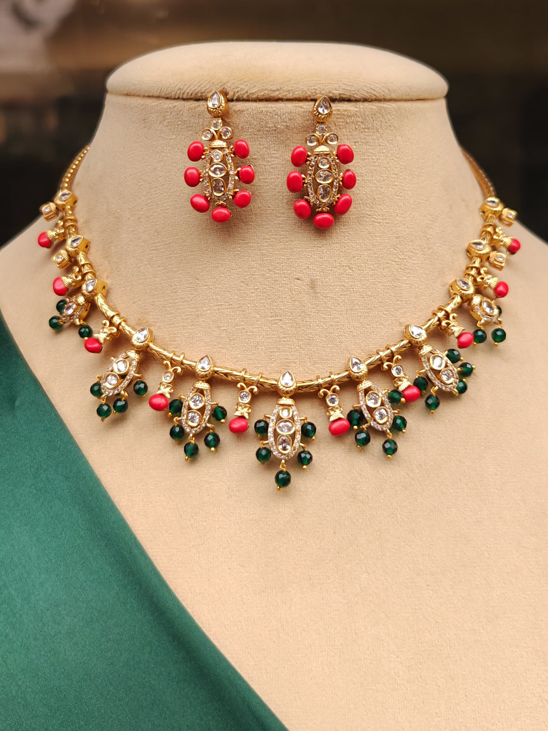 Close-up of an ornate traditional (Gold Polish) Collar jewellery set and earrings with Colored Stone, Beads and American Diamonds. Festive Diwali outfit paired with a colorful Colored Stone necklace. Mehendi ceremony look completed with a Colored Stone  jewelry set.