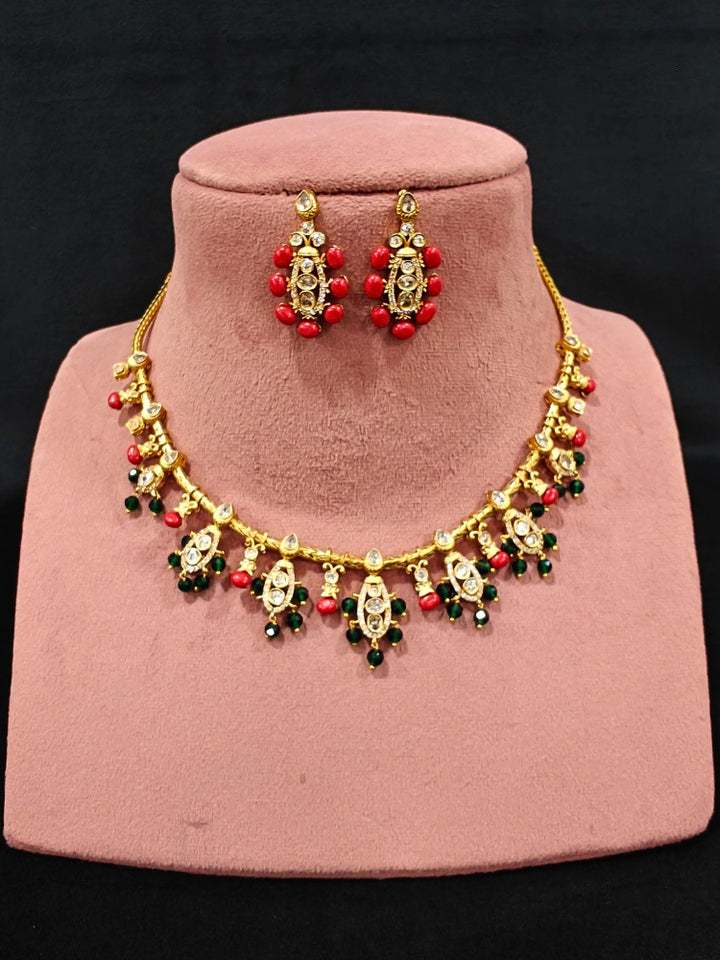 Close-up of an ornate traditional (Gold Polish) Collar jewellery set and earrings with Colored Stone, Beads and American Diamonds. Festive Diwali outfit paired with a colorful Colored Stone necklace. Mehendi ceremony look completed with a Colored Stone  jewelry set.