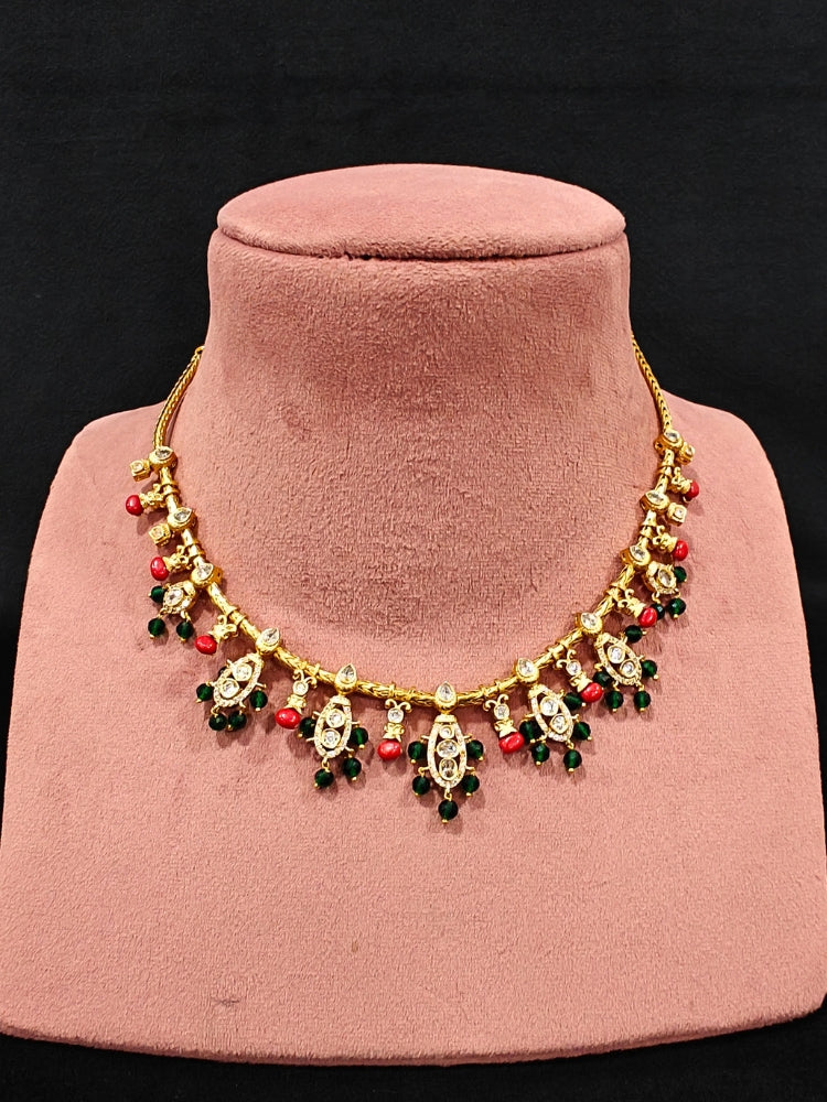 Close-up of an ornate traditional (Gold Polish) Collar jewellery set and earrings with Colored Stone, Beads and American Diamonds. Festive Diwali outfit paired with a colorful Colored Stone necklace. Mehendi ceremony look completed with a Colored Stone  jewelry set.
