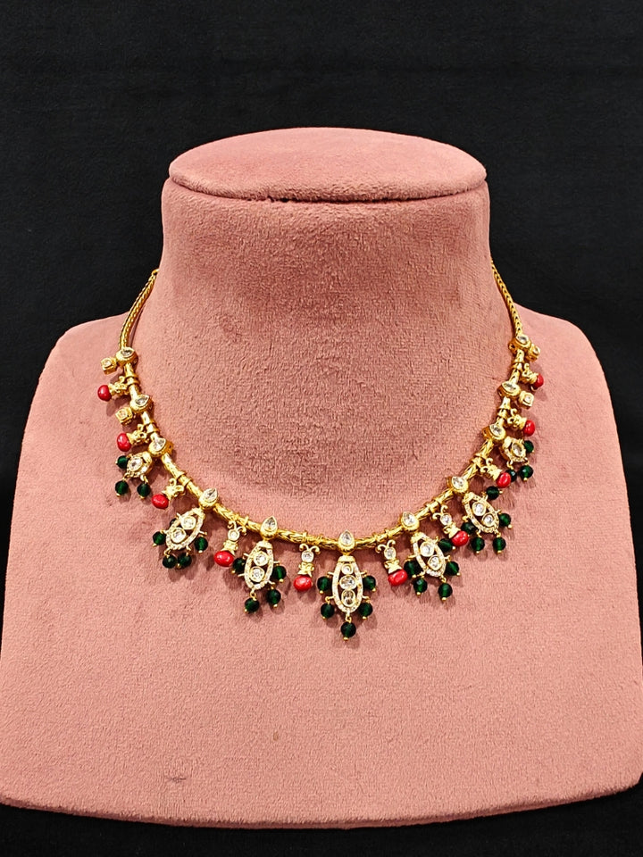 Close-up of an ornate traditional (Gold Polish) Collar jewellery set and earrings with Colored Stone, Beads and American Diamonds. Festive Diwali outfit paired with a colorful Colored Stone necklace. Mehendi ceremony look completed with a Colored Stone  jewelry set.
