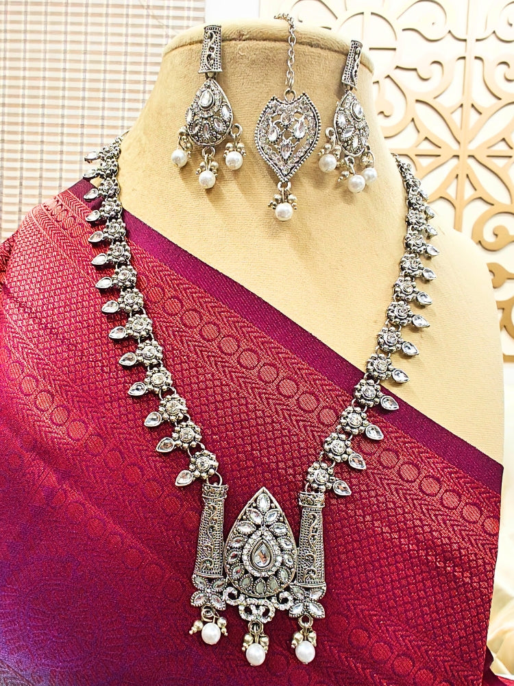 Close-up of an ornate traditional (Silver Polish) Oxidised  jewellery set and earrings and maangtikka Kundan and Pearls. Festive saree styling with a premium artificial Kundan necklace. Saree look completed with a traditional artificial Kundan set.