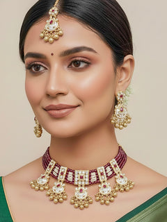 Close-up of a woman wearing an ornate traditional Ruby Pink Meenakari gold Choker jewellery set and earrings and maangtikka with Colored Stones, Pearls, Meenakari, Kundan and Crystal Beads. Festive Diwali outfit paired with a colorful Meenakari necklace. Close-up of detailed enamel craftsmanship in Meenakari jewelry.