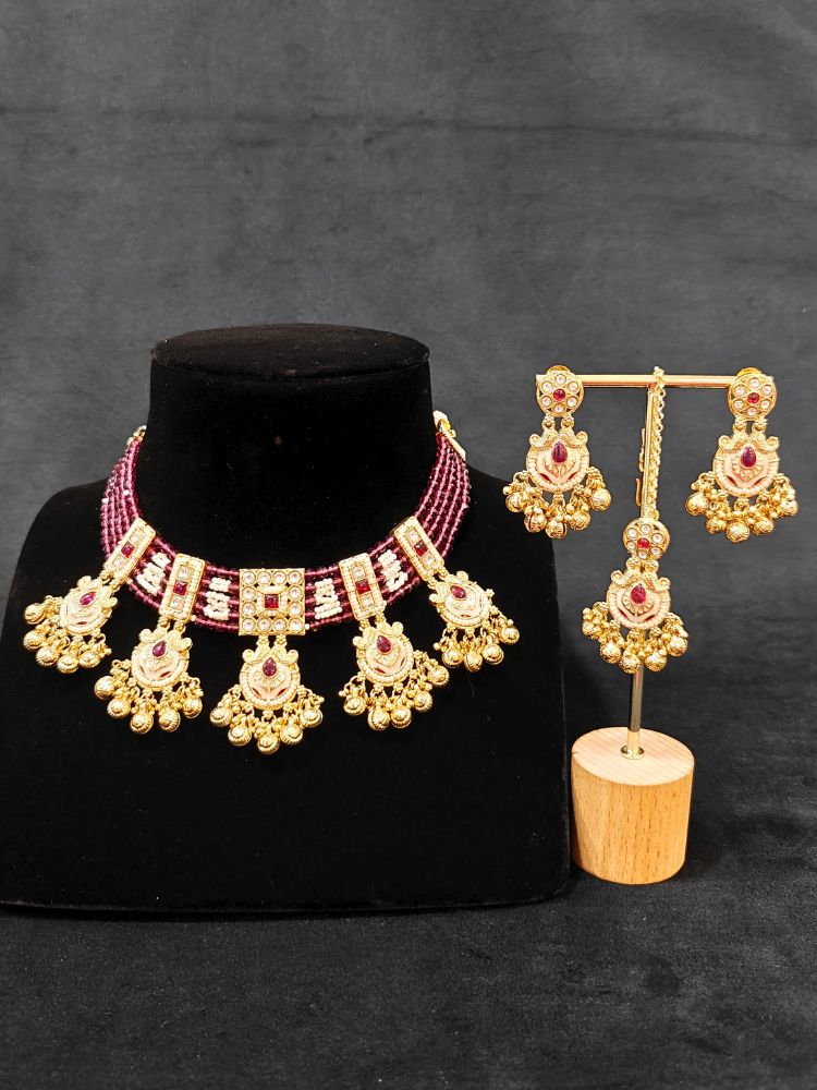 Close-up of an ornate traditional Ruby Pink Meenakari gold Choker jewellery set and earrings and maangtikka with Colored Stones, Pearls, Meenakari, Kundan and Crystal Beads. Festive Diwali outfit paired with a colorful Meenakari necklace. Close-up of detailed enamel craftsmanship in Meenakari jewelry.