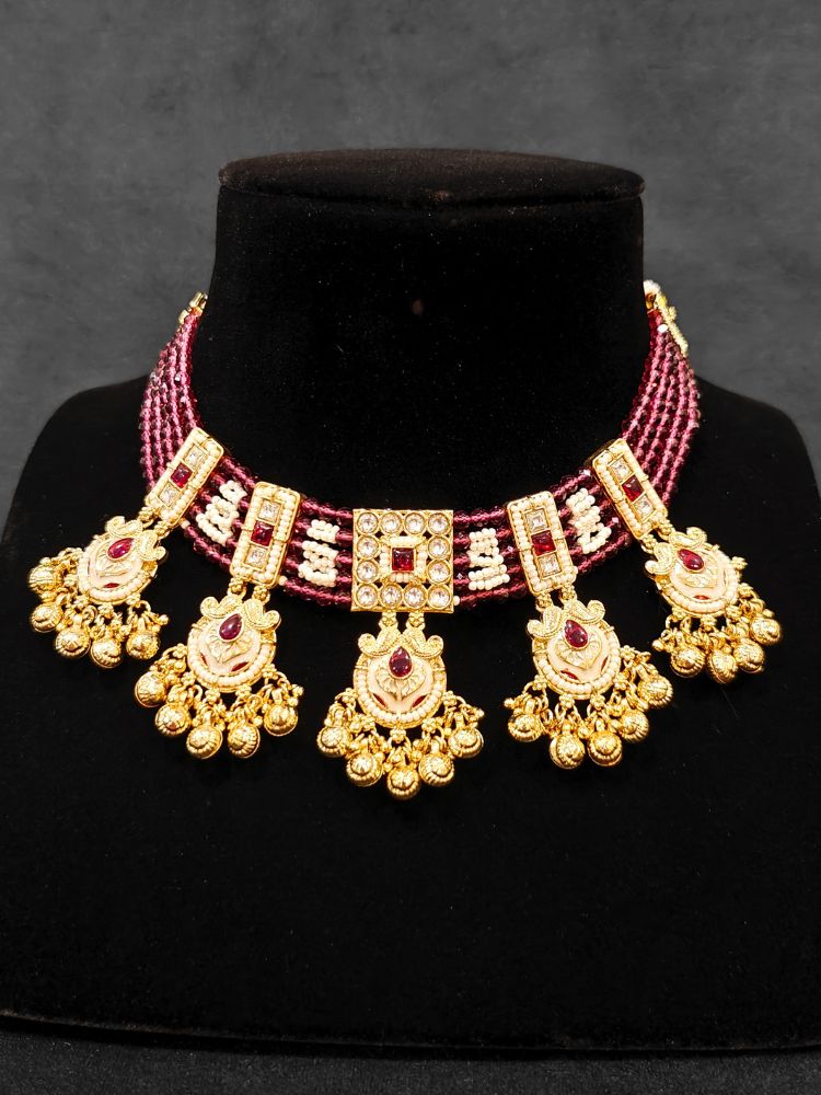 Close-up of an ornate traditional Ruby Pink Meenakari gold Choker jewellery set and earrings and maangtikka with Colored Stones, Pearls, Meenakari, Kundan and Crystal Beads. Festive Diwali outfit paired with a colorful Meenakari necklace. Close-up of detailed enamel craftsmanship in Meenakari jewelry.
