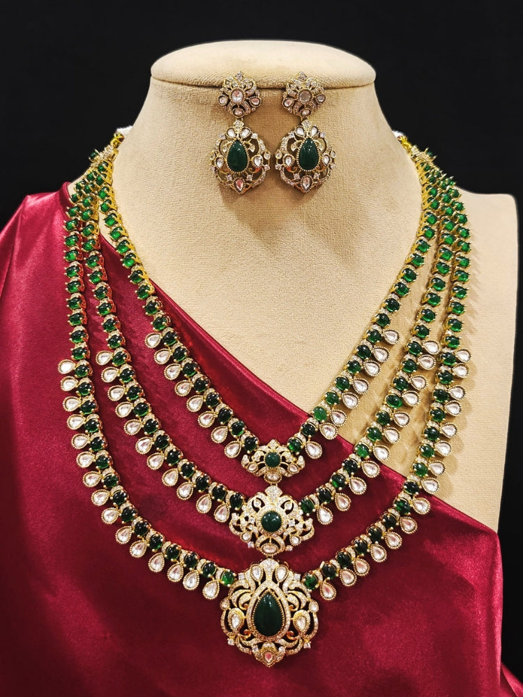 Close-up of an ornate traditional Green Heritage gold Long Layered jewellery set and earrings with colored Stone, Kundan and American Diamond. Mehendi ceremony styling featuring a premium heritage artificial jewelry piece. Styling a vintage heritage artificial necklace for a reception party.