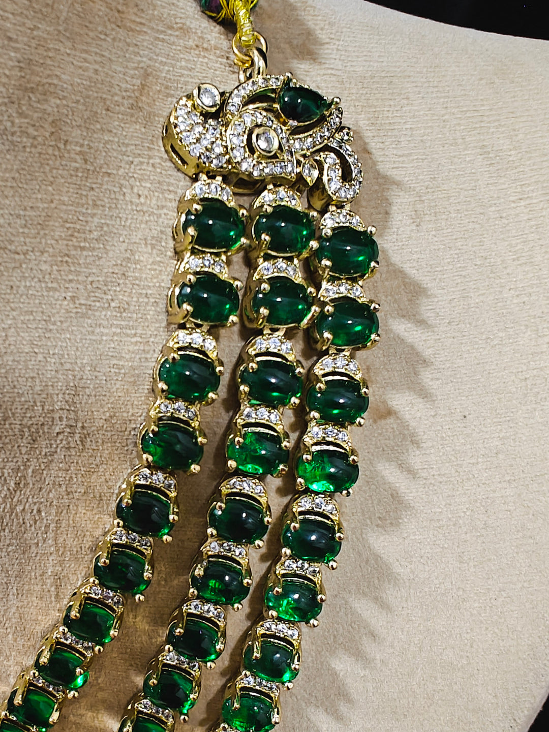 Close-up of an ornate traditional Green Heritage gold Long Layered jewellery set and earrings with colored Stone, Kundan and American Diamond. Mehendi ceremony styling featuring a premium heritage artificial jewelry piece. Styling a vintage heritage artificial necklace for a reception party.