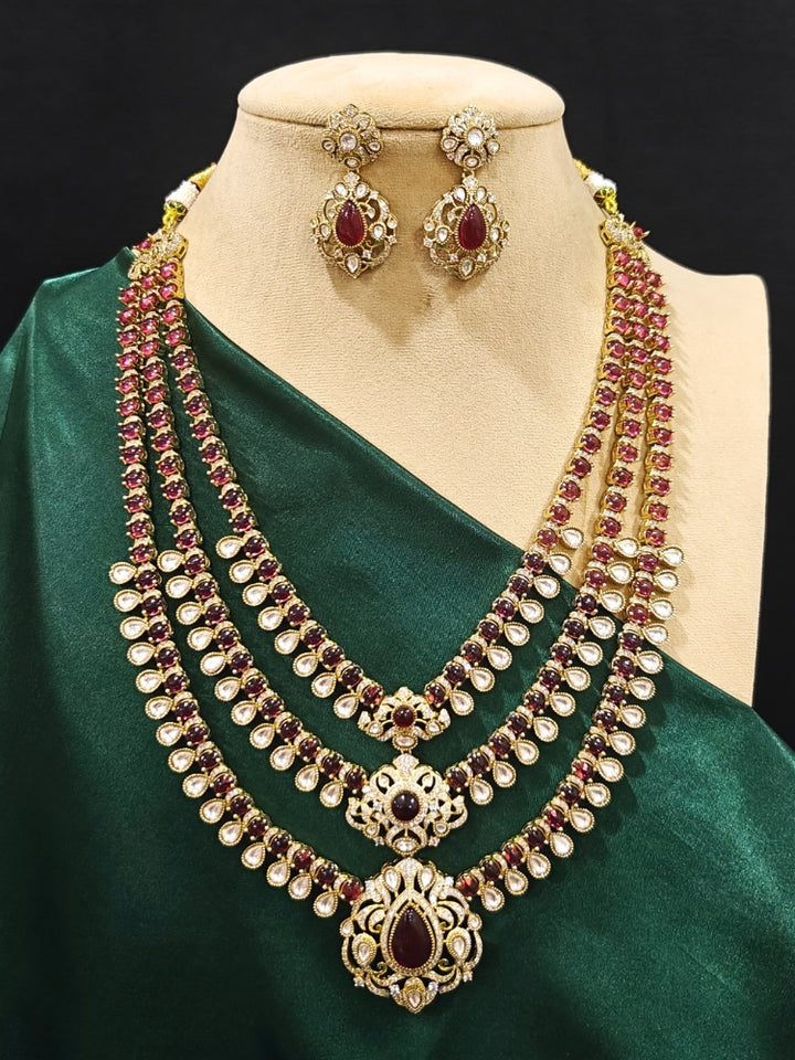 Close-up of an ornate traditional Red Heritage gold Long Layered jewellery set and earrings with colored Stone, Kundan and American Diamond. Mehendi ceremony styling featuring a premium heritage artificial jewelry piece. Traditional Indian look completed with a heritage artificial jewelry set.