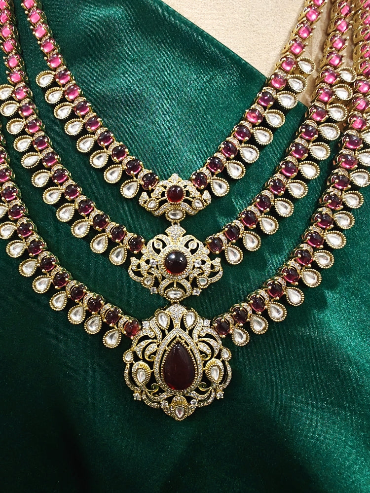 Close-up of an ornate traditional Red Heritage gold Long Layered jewellery set and earrings with colored Stone, Kundan and American Diamond. Mehendi ceremony styling featuring a premium heritage artificial jewelry piece. Traditional Indian look completed with a heritage artificial jewelry set.