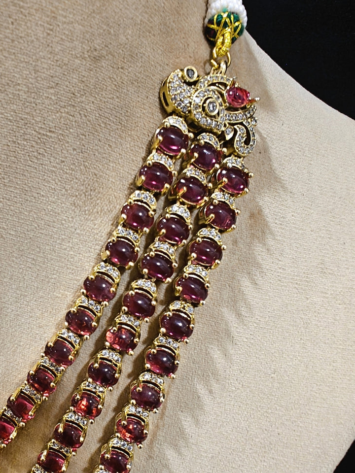 Close-up of an ornate traditional Red Heritage gold Long Layered jewellery set and earrings with colored Stone, Kundan and American Diamond. Mehendi ceremony styling featuring a premium heritage artificial jewelry piece. Traditional Indian look completed with a heritage artificial jewelry set.