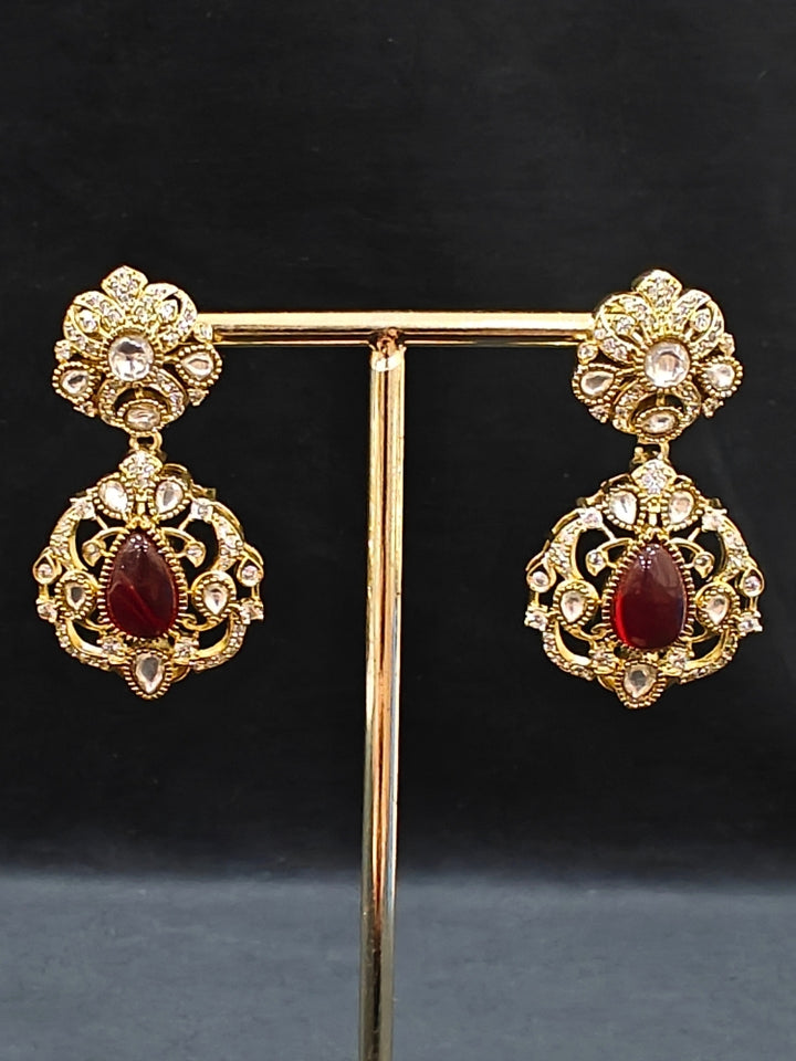 Close-up of an ornate traditional Red Heritage gold Long Layered jewellery set and earrings with colored Stone, Kundan and American Diamond. Mehendi ceremony styling featuring a premium heritage artificial jewelry piece. Traditional Indian look completed with a heritage artificial jewelry set.