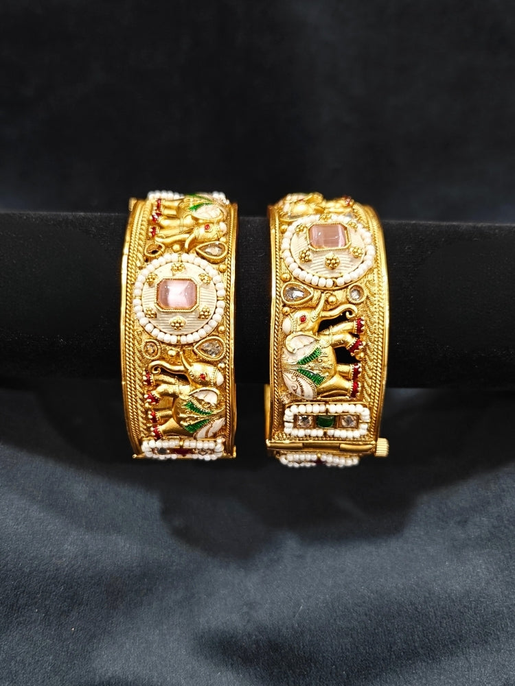 Close-up of an ornate traditional Rajwadi gold Bangle with Bandhai Work, Meenakari and Mint Pink Colored Stone. Anti-tarnish artificial Rajwadi bangles for long functions. Traditional Indian jewelry look with artificial Rajwadi bangles. Close-up of enamel work in Meenakari artificial wedding Bangles.