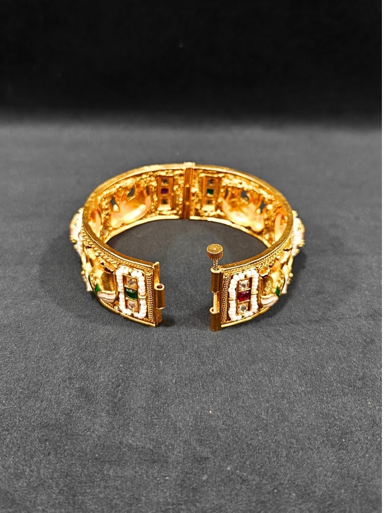 Close-up of an ornate traditional Rajwadi gold Bangle with Bandhai Work, Meenakari and Mint Pink Colored Stone. Anti-tarnish artificial Rajwadi bangles for long functions. Traditional Indian jewelry look with artificial Rajwadi bangles. Close-up of enamel work in Meenakari artificial wedding Bangles.