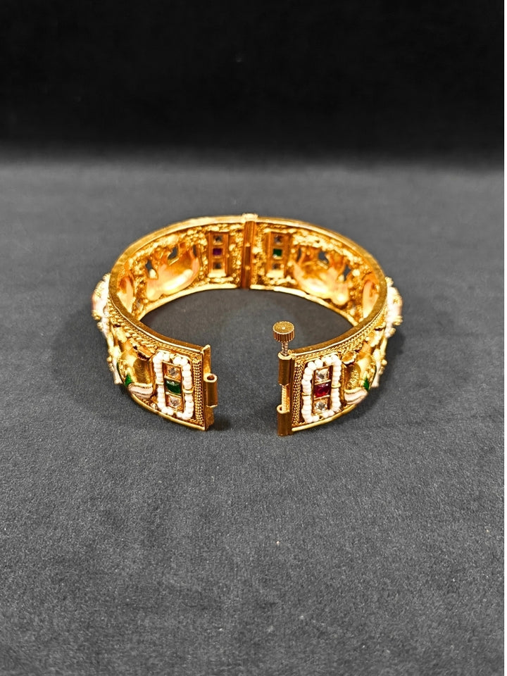 Close-up of an ornate traditional Rajwadi gold Bangle with Bandhai Work, Meenakari and Mint Pink Colored Stone. Anti-tarnish artificial Rajwadi bangles for long functions. Traditional Indian jewelry look with artificial Rajwadi bangles. Close-up of enamel work in Meenakari artificial wedding Bangles.