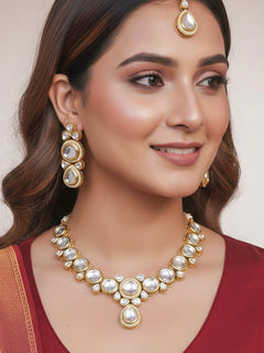 Close-up of a woman wearing an ornate traditional (Gold Polish) White Collar jewellery set and earrings and maangtikka with Kundan and American Diamonds. Woman wearing trending Kundan artificial jewelry for wedding season in India. Bride wearing a royal Kundan artificial necklace for wedding rituals.