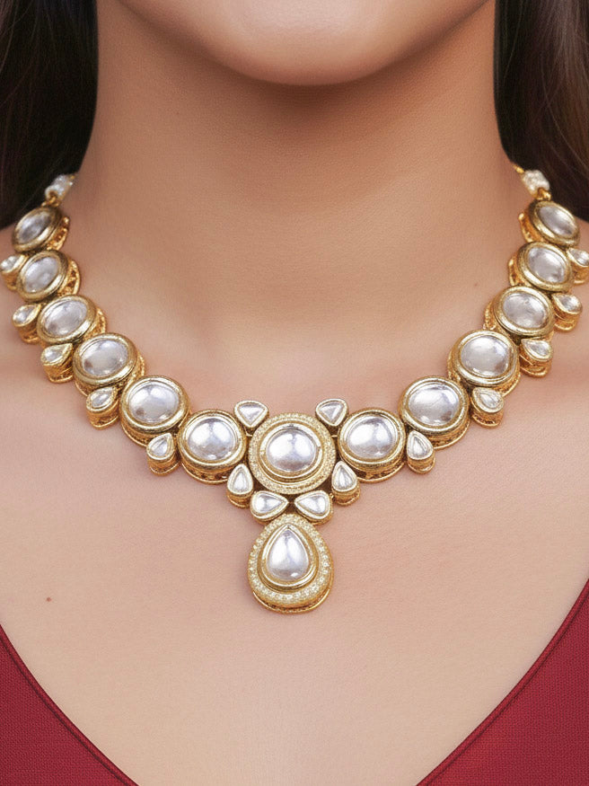 Close-up of a woman wearing an ornate traditional (Gold Polish) White Collar jewellery set and earrings and maangtikka with Kundan and American Diamonds. Woman wearing trending Kundan artificial jewelry for wedding season in India. Bride wearing a royal Kundan artificial necklace for wedding rituals.