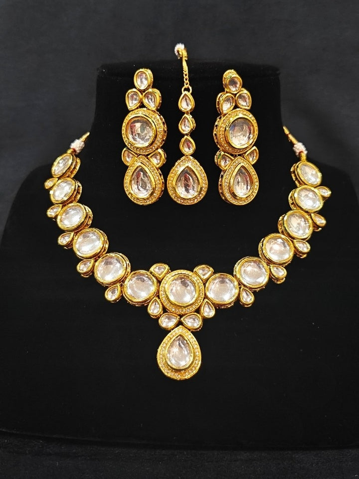 Close-up of an ornate traditional (Gold Polish) White Collar jewellery set and earrings and maangtikka with Kundan and American Diamonds. A trending Kundan artificial jewelry for wedding season in India. Bride wearing a royal Kundan artificial necklace for wedding rituals.