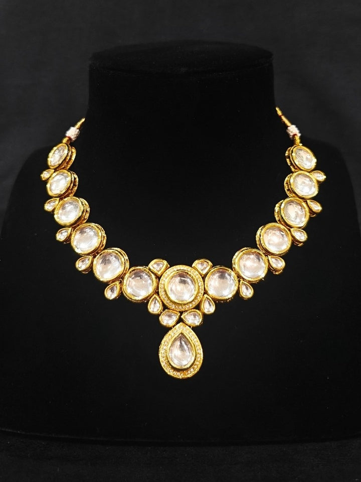 Close-up of an ornate traditional (Gold Polish) White Collar jewellery set and earrings and maangtikka with Kundan and American Diamonds. A trending Kundan artificial jewelry for wedding season in India. Bride wearing a royal Kundan artificial necklace for wedding rituals.