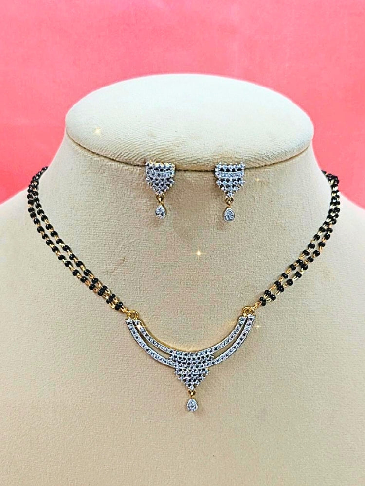 Diksha Mangalsutra—a gold necklace with black mangalsutra beads and matching earrings, pendant featuring sparkling American Diamonds—set against a cream dummy, perfect for your wedding ceremony dress. Diamond mangalsutra. Modern mangalsutra. 