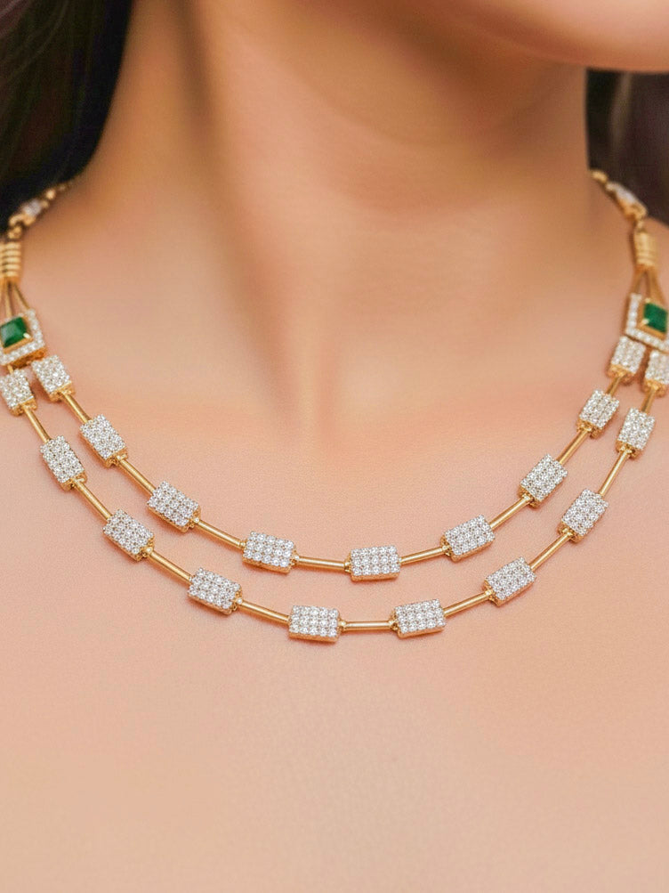 Close-up of a woman wearing an ornate Indo-western Green (gold Polish) Collar Layered Diamond jewellery set and earrings with American Diamond and Colored Stone. Party wear outfit completed with a lightweight American diamond necklace. Reception-ready look featuring a statement American diamond jewelry set.