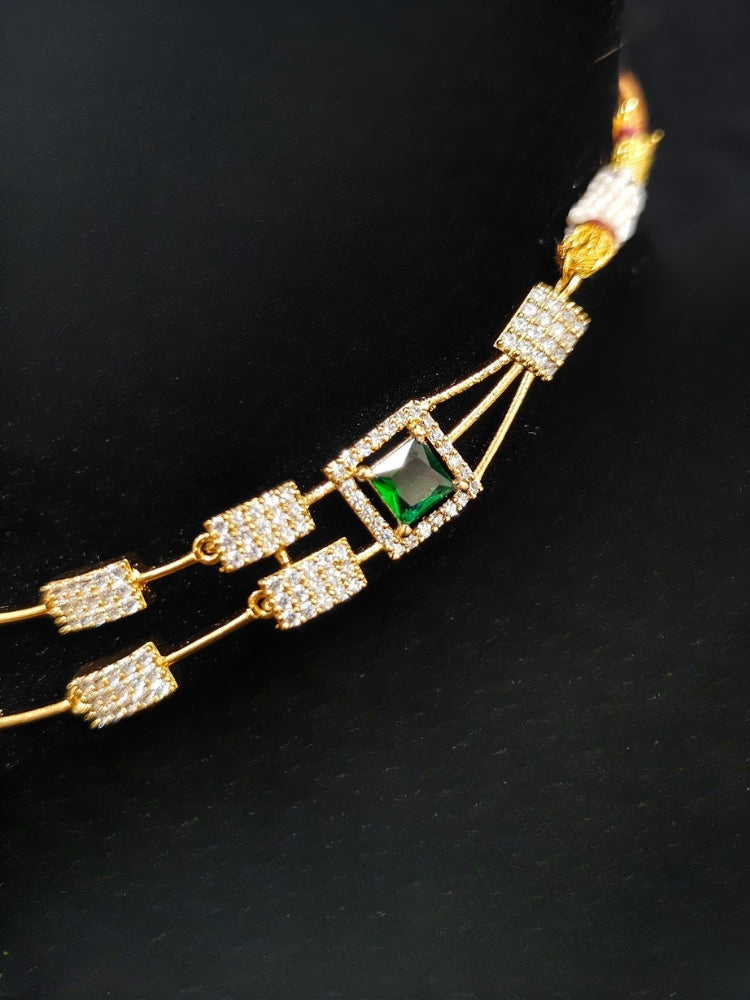 Close-up of an ornate Indo-western Green (gold Polish) Collar Layered Diamond jewellery set and earrings with American Diamond and Colored Stone. Party wear outfit completed with a lightweight American diamond necklace. Reception-ready look featuring a statement American diamond jewelry set.