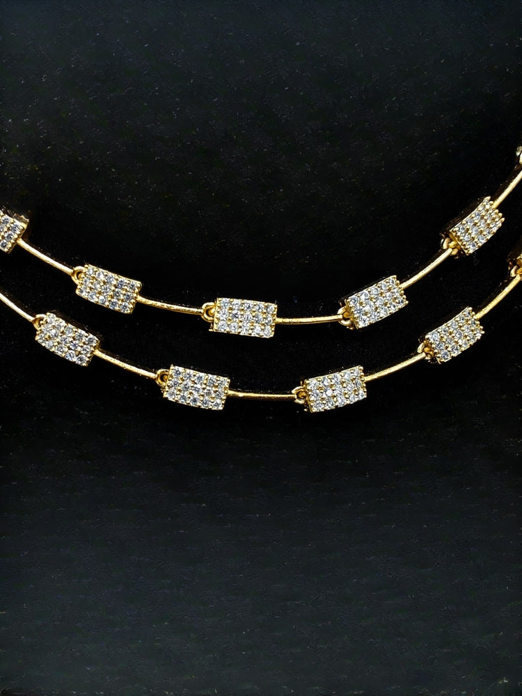 Close-up of an ornate Indo-western Green (gold Polish) Collar Layered Diamond jewellery set and earrings with American Diamond and Colored Stone. Party wear outfit completed with a lightweight American diamond necklace. Reception-ready look featuring a statement American diamond jewelry set.