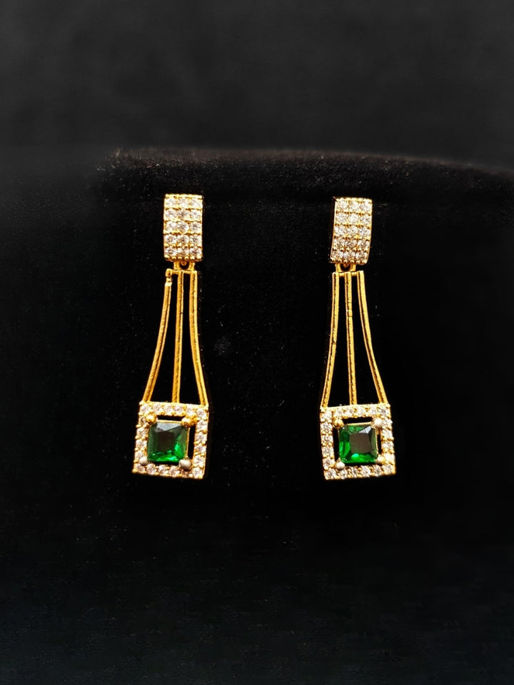 Close-up of an ornate Indo-western Green (gold Polish) Collar Layered Diamond jewellery set and earrings with American Diamond and Colored Stone. Party wear outfit completed with a lightweight American diamond necklace. Reception-ready look featuring a statement American diamond jewelry set.