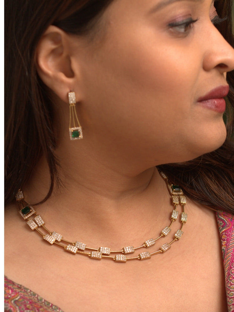 Close-up of a woman wearing an ornate Indo-western Green (gold Polish) Collar Layered Diamond jewellery set and earrings with American Diamond and Colored Stone. Party wear outfit completed with a lightweight American diamond necklace. Reception-ready look featuring a statement American diamond jewelry set.