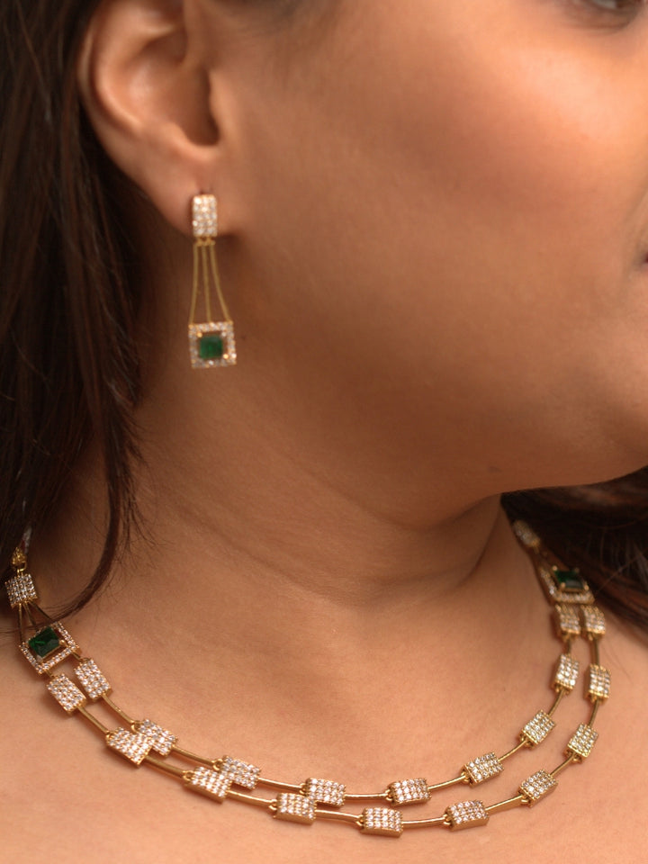 Close-up of a woman wearing an ornate Indo-western Green (gold Polish) Collar Layered Diamond jewellery set and earrings with American Diamond and Colored Stone. Party wear outfit completed with a lightweight American diamond necklace. Reception-ready look featuring a statement American diamond jewelry set.