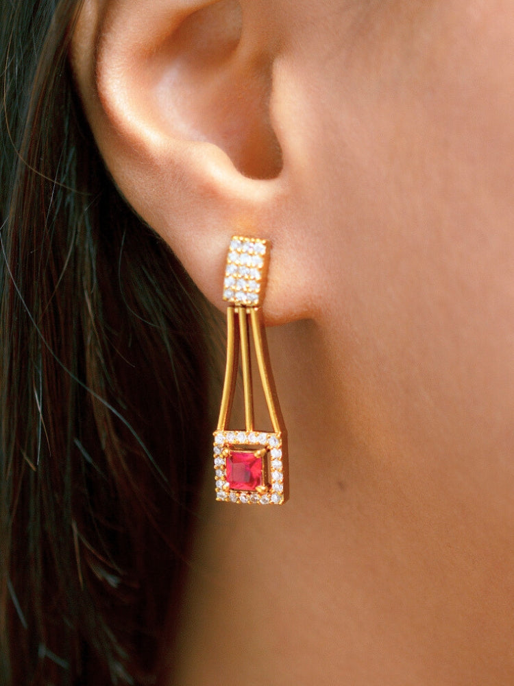 A woman wears the Diora Red Necklace Set, a gold party jewelry set featuring a red 2 layer necklace set made with  American diamonds and red gemstones at both the corners, paired with matching earrings. Only her lower face and neck are visible.