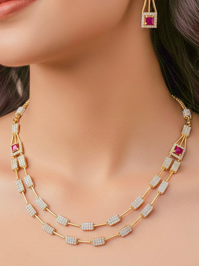 Close-up of a woman wearing an ornate Indo-western Red (gold Polish) Collar Layered Diamond jewellery set and earrings with American Diamond and Colored Stone. Party wear outfit completed with a lightweight American diamond necklace. Reception-ready look featuring a statement American diamond jewelry set.