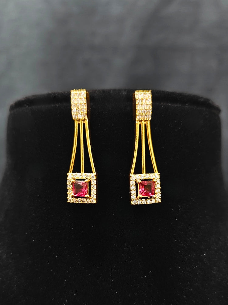 Close-up of an ornate Indo-western Red (gold Polish) Collar Layered Diamond jewellery set and earrings with American Diamond and Colored Stone. Party wear outfit completed with a lightweight American diamond necklace. Reception-ready look featuring a statement American diamond jewelry set.