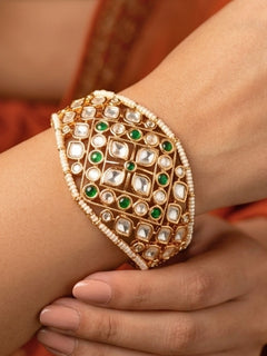 Close-up of a woman wearing an ornate traditional (Gold Polish) Green Bracelet with Polki, Green Colored Stone and Pearl. Close-up of a high-quality imitation Polki bracelet for festive wear. Woman showcasing a premium artificial Polki bracelet for wedding celebrations.