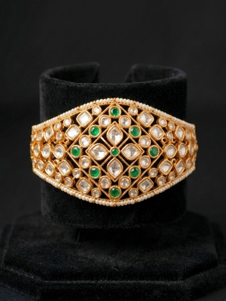 Close-up of an ornate traditional (Gold Polish) Green Bracelet with Polki, Green Colored Stone and Pearl. Close-up of a high-quality imitation Polki bracelet for festive wear. Woman showcasing a premium artificial Polki bracelet for wedding celebrations.