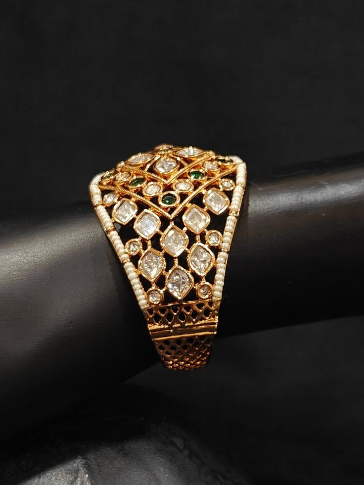 Close-up of an ornate traditional (Gold Polish) Green Bracelet with Polki, Green Colored Stone and Pearl. Close-up of a high-quality imitation Polki bracelet for festive wear. Woman showcasing a premium artificial Polki bracelet for wedding celebrations.