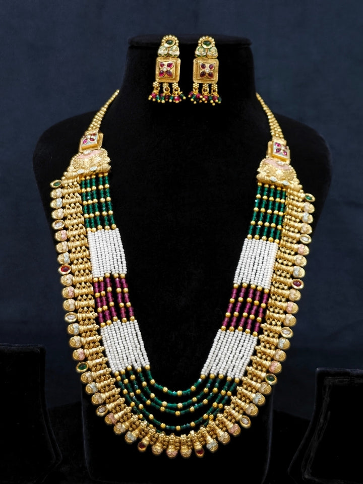 Close-up of an ornate traditional (Gold Polish) Pink & Green Long jewellery set and earrings with Pearls, Green & Pink Crystal Beads and Meenakari. Festive Diwali outfit paired with a colorful Meenakari necklace. Wedding function styling with a premium Meenakari imitation necklace.