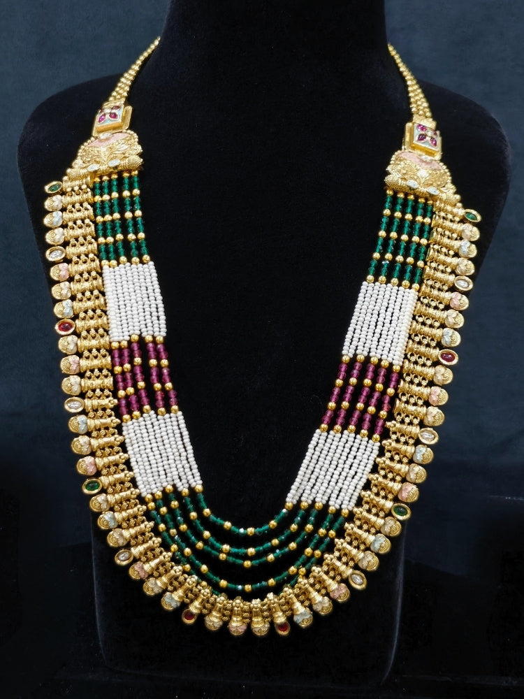 Close-up of an ornate traditional (Gold Polish) Pink & Green Long jewellery set and earrings with Pearls, Green & Pink Crystal Beads and Meenakari. Festive Diwali outfit paired with a colorful Meenakari necklace. Wedding function styling with a premium Meenakari imitation necklace.